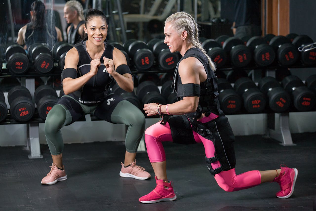 get-in-touch Two women engaged in strength training at a gym, showing determination.