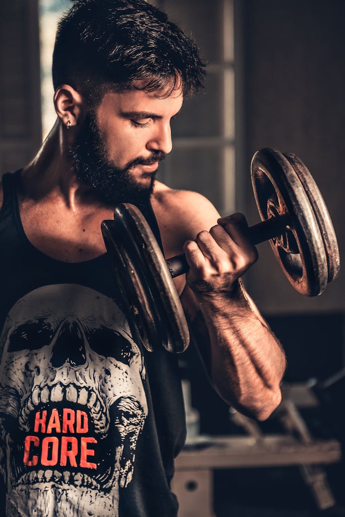 services-bg Bearded man in gym lifting a heavy dumbbell, showcasing strength and fitness.